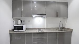 cocina con armarios de acero inoxidable y microondas en BHomed Furnished Apartments en Kuwait