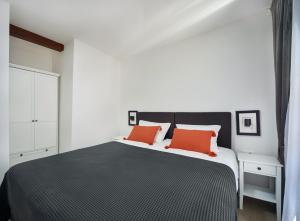 een slaapkamer met een zwart-wit bed met oranje kussens bij Cardo Apartments in Poreč +67 foto's