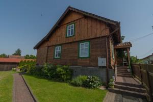 Casa de madera con ventanas verdes y patio en Dom w Krutyni, en Krutyń