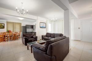 een woonkamer met twee leren banken en een tafel bij Nissi Villa Sotia in Ayia Napa