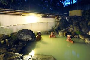 Un gruppo di uomini in una vasca idromassaggio con rocce di Okunikko Konishi Hotel a Nikko