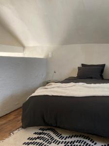 1 dormitorio con 1 cama con manta negra y alfombra en guesthouse L'Officine, en Lincent