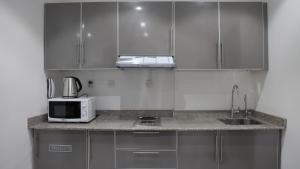 cocina con armarios de acero inoxidable y microondas en BHomed Furnished Apartments en Kuwait