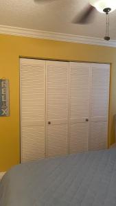 a bedroom with white closets in a yellow wall at lovely 2BED 2BA vacation rental near the Beach in Pompano Beach