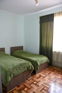 1 Schlafzimmer mit 2 Betten mit grüner Bettwäsche und einem Fenster in der Unterkunft Manana Guesthouse in Marmarik