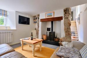 a living room with a table and a fireplace at Finest Retreats - Farm Cottage in Nancledra