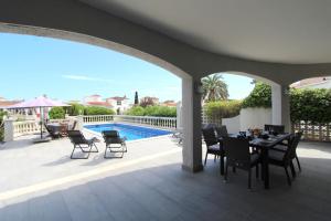 een patio met een tafel en stoelen en een zwembad bij LEON INMO Villa Frida - 11790 in Empuriabrava