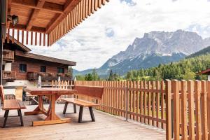 a wooden deck with a table and bench and mountains at Alpenchalets Biberwier Zugspitze by ALPS RESORTS in Biberwier