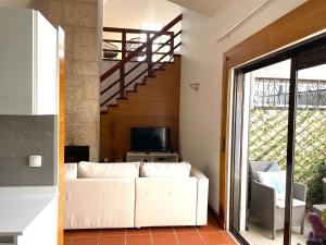 a living room with a white couch and a staircase at TOP BEACH HOUSE in Costa da Caparica