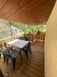 um deque de madeira com uma mesa e cadeiras em LE PASSE-MONTAGNE Bel appartement avec terrasse dans vieille ferme de montagne rénovée em Les Orres