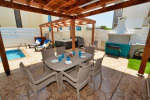 een terras met een tafel en stoelen en een barbecue bij Nissi Villa Sotia in Ayia Napa