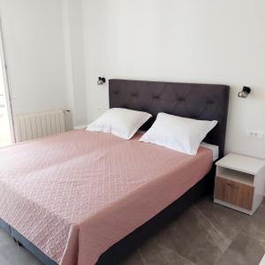 a bedroom with a large bed with pink sheets and white pillows at Apartman Dado Podgora in Podgora