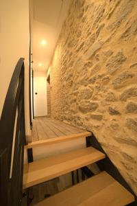 a hallway with wooden stairs and a stone wall at Maison atypique centre bourg 15kms du PDF et Parc Maulévrier in Mauléon