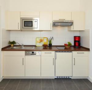 eine Küche mit weißen Schränken und einem Waschbecken in der Unterkunft Ferienwohnung Kargoll Wydra in Heringsdorf in Heringsdorf