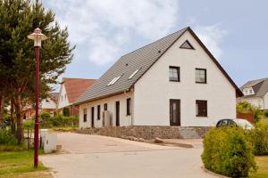 ein weißes Haus mit einem schwarzen Dach und einem Straßenlicht in der Unterkunft Ferienwohnung Kargoll Wydra in Heringsdorf in Heringsdorf