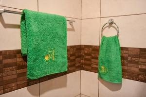 2 asciugamani verdi appesi a un appendiabiti in bagno di Manana Guesthouse a Marmarik