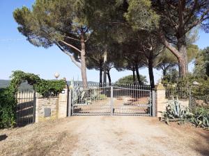 um portão para uma entrada com árvores ao fundo em Podere Belvedere Villa Classic Tuscan em Magliano in Toscana