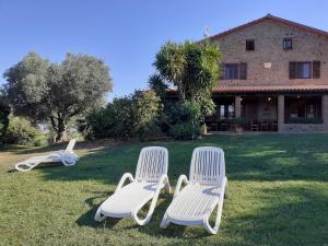 drie witte stoelen in het gras voor een huis bij Podere Belvedere Villa Classic Tuscan in Magliano in Toscana