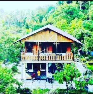 une maison en bois avec des personnes debout devant elle dans l'établissement Air Manis Secret Surfcamp, à Taluk Batung