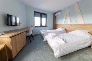 two beds in a room with a desk and a television at Hotel Verticalplus in Haskovo