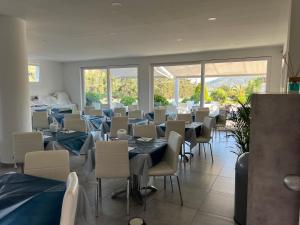una sala da pranzo con tavoli, sedie e finestre di Hotel Barbarossa a Porto Azzurro