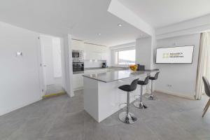 a white kitchen with a counter and stools at Apartamento Anamsa in Port de Pollensa +35 photos