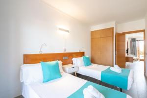 Dos camas en una habitación de hotel con azul y blanco en Apartamentos Estanques en Colonia de Sant Jordi