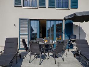 a patio with a table and chairs and an umbrella at Reetland am Meer - Luxus Reetdachvilla mit 3 Schlafzimmern, Sauna und Kamin F20 in Dranske