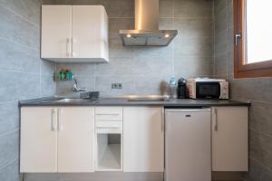 a kitchen with white cabinets and a microwave at Apartamentos Estanques in Colonia Sant Jordi