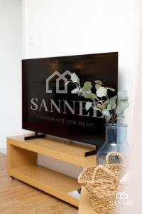 a television on a stand with a vase with a plant at Apartament Premium Marin - Pinea Apartments Pobierowo in Pobierowo