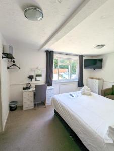 1 dormitorio con cama, escritorio y ventana en Cottage Court Hotel, en Tenby