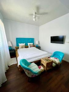 1 dormitorio con 1 cama y 2 sillas azules en Chambre confortable dans une ambiance hôtel de charme avec piscine en Saint-Louis