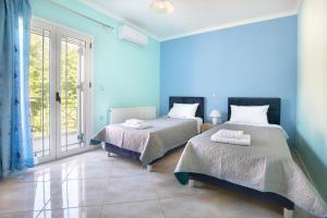 Duas camas num quarto com paredes azuis em βΙΛΑ ΕΜΜΑΝΟΥΕΛΑ em Sami
