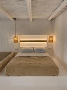 a bedroom with a bed with two lights on it at Yialos Ios Hotel in Ios Chora