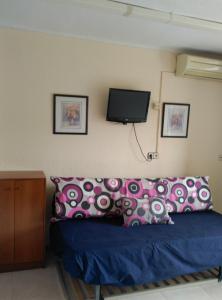 um quarto com uma cama com almofadas roxas e uma televisão em Estudio en La Pineda em La Pineda
