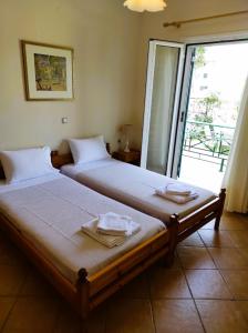 two beds in a room with a sliding glass door at Oikia Dinachris in Agios Georgios