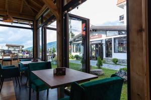 un restaurante con sillas verdes, mesa y ventanas en No 107 Predeal en Predeal