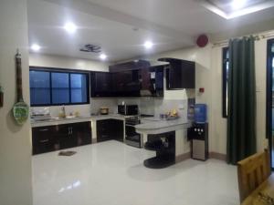 a kitchen with black cabinets and a white floor at blue starfish villa in Panglao