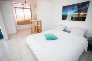 a white bedroom with two beds and a table at BOULEVARD LEGITIMUS in Pointe-à-Pitre