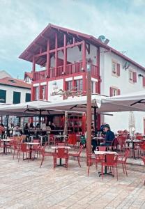 a group of tables and umbrellas in front of a building at Hotel du Fronton in Bidart