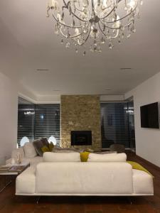 ein Wohnzimmer mit einem weißen Sofa und einem Kronleuchter in der Unterkunft Piscina e relax nelle Langhe Villa Gaia in Bra