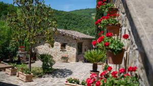 un jardin avec des fleurs rouges et un bâtiment en pierre dans l'établissement Agriturismo I Pietrini, à Pérouse