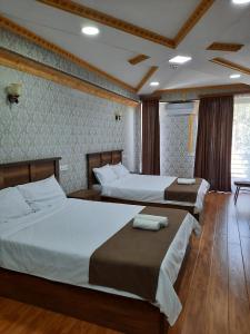 two beds in a room with wooden floors at Hotel LU-MA in Tbilisi City