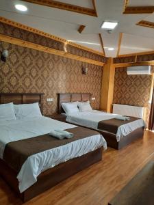 two beds in a room with wooden floors at Hotel LU-MA in Tbilisi City