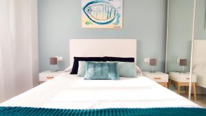 a bedroom with a large white bed with blue pillows at Laguna Beach Paradise - Alojamientos La Torre in Torrox Costa