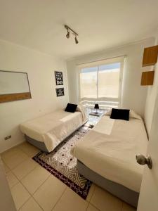 two beds in a room with a window at Apart Mejillones - Dpto 22 in Mejillones
