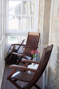 two rocking chairs sitting on a porch with a window at PISO CÉNTRICO AMPLIO, LUMINOSO, EN CASA DE PIEDRA in Guitiriz