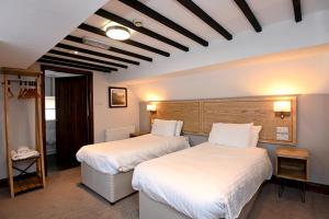 2 Betten in einem Hotelzimmer mit weißer Bettwäsche in der Unterkunft Swan, Thatcham by Marston's Inns in Thatcham