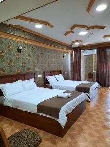 a bedroom with two beds and a wall with green wallpaper at Hotel LU-MA in Tbilisi City