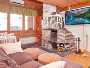 a living room with a stone fireplace and a tv at Holiday Home Lomasyväri 810 by Interhome in Nilsiä